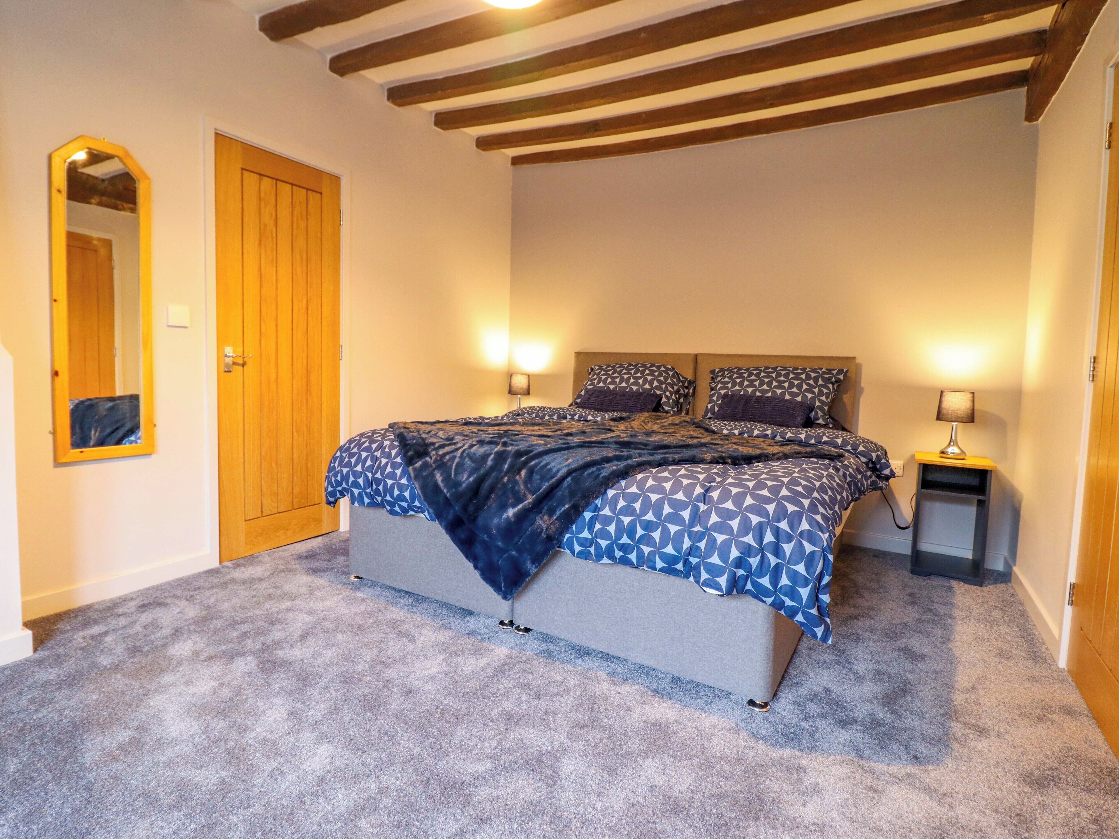A bedroom with a bed, two bedside lamps, a wooden door, and a mirror.