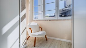 Ein Eckzimmer mit weißem Stuhl, einem Fenster und Holzboden.
