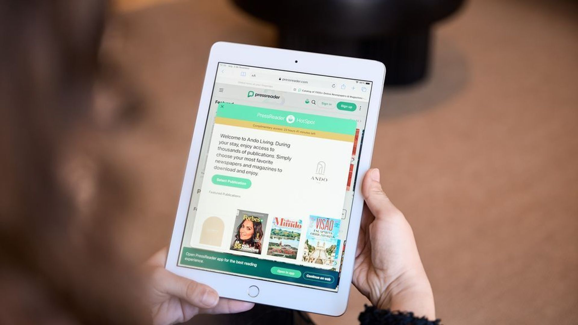 Un tablet mostra un'app di notizie con un messaggio di benvenuto, pubblicazioni in evidenza e una sezione 'Hot Spot'.