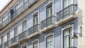 Fachada de edificio con múltiples ventanas y balcones, destacando intrincados diseños de azulejos azules y blancos.