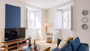 Una sala de estar moderna con televisor, sofá, mesa de centro y lámpara.