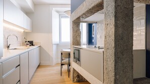 Una cocina moderna con armarios blancos, horno empotrado y una pared decorativa de piedra.