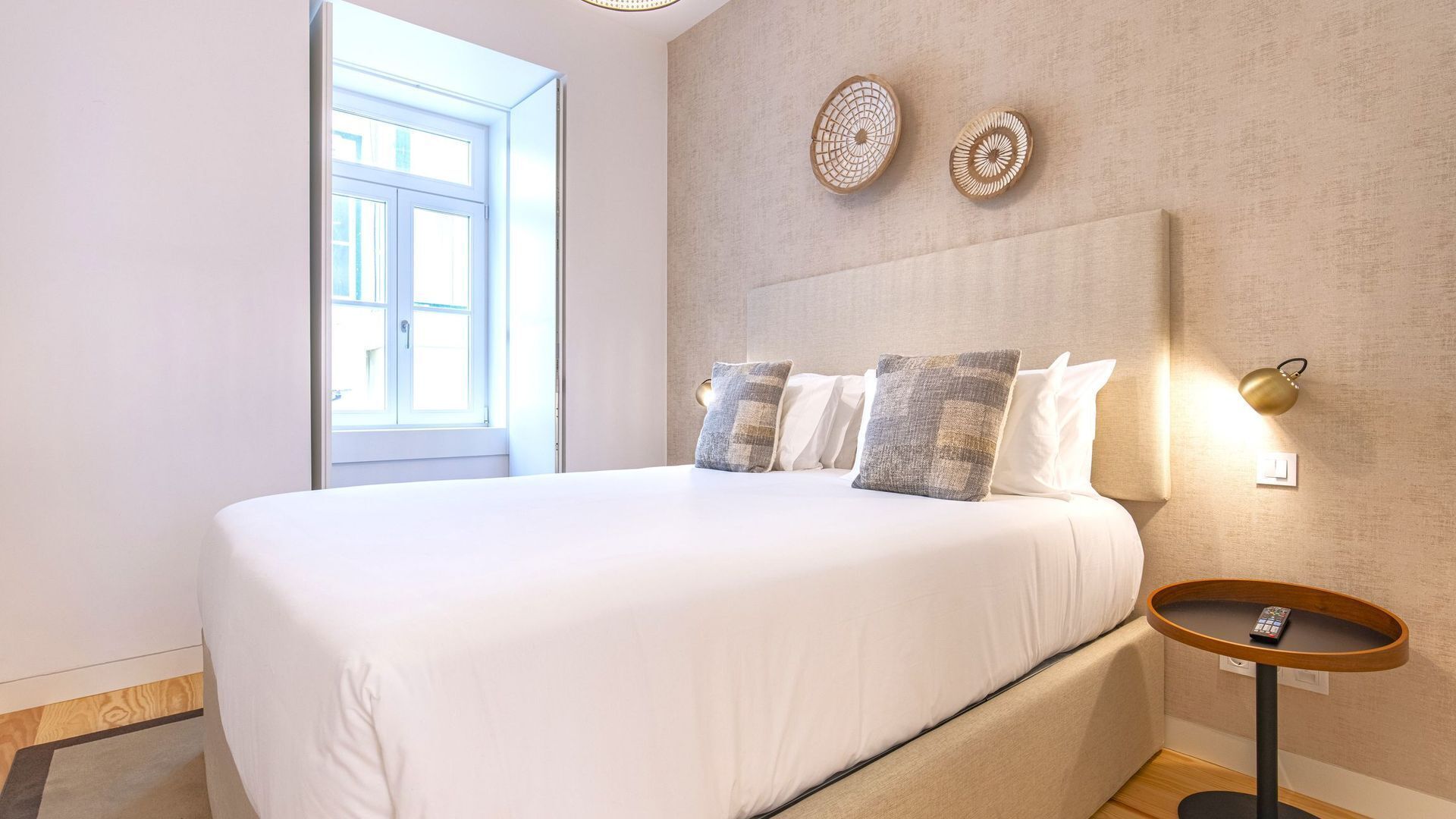 Un dormitorio con una cama grande, una mesita de noche con un control remoto y una lámpara de pared.