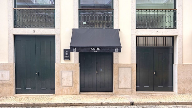 A building with three black doors, each marked with a number (3, 4, 5). Above the central door, there is a black awning with the logo "ANDO Living". - Ando Living - Douradores House - 301 (Lisboa)