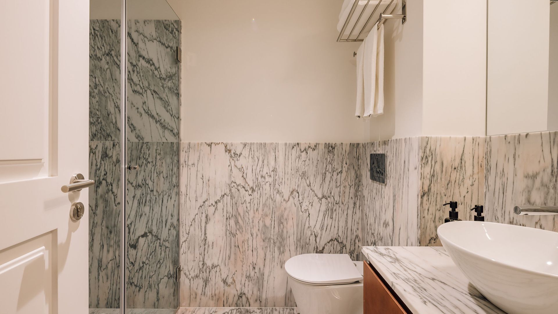 Une salle de bain avec une douche en marbre, des toilettes, un lavabo et un miroir.