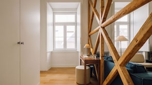 A room with a wooden beam structure, a sofa, a table with a lamp, and a window. - Ando Living - Santa Justa 79 House - 201 (Lisboa)