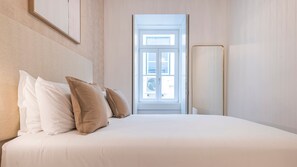 A bedroom with a bed, pillows, a nightstand, a window, and a door. - Ando Living - Douradores House - 401 (Lisboa)