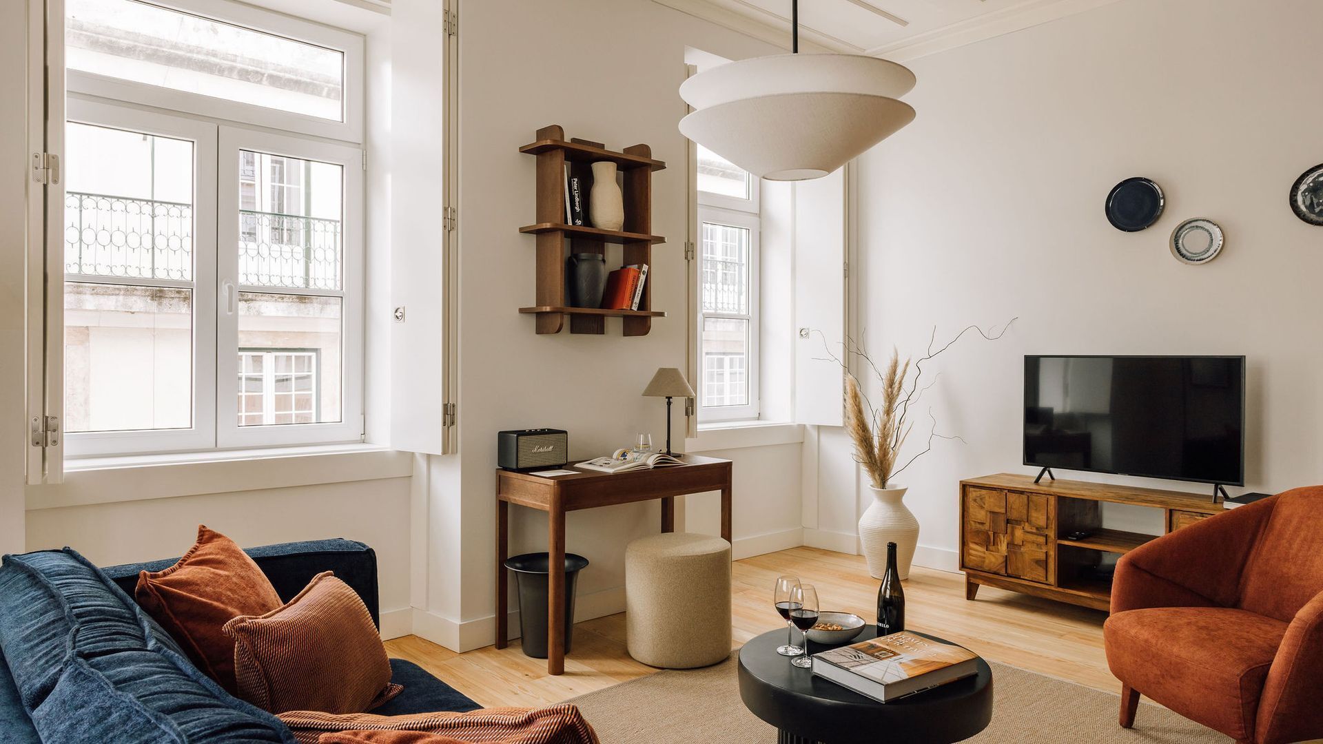 Ein Wohnzimmer mit Sofa, Sessel, Couchtisch, Bücherregal und Fernseher.