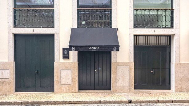 Un edificio con tre porte nere, ognuna con una piccola insegna sopra.