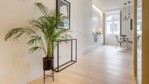 Un appartamento moderno con un'ampia pianta in vaso, un'opera d'arte incorniciata e un'area pranzo con tavolo e sedie.