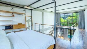 A modern bedroom with a large bed, a wooden desk, a built-in shelf, and a balcony with a glass railing. - Urban Oasis Loft by GORO (Kabupaten Badung)