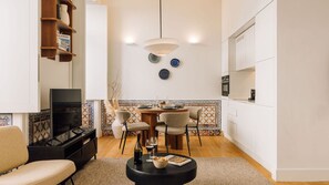 A modern living room with a TV, sofa, coffee table, and dining area with chairs and a table.