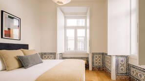 Ein Schlafzimmer mit Bett, Kissen, einem Fenster und einer gefliesten Wand.