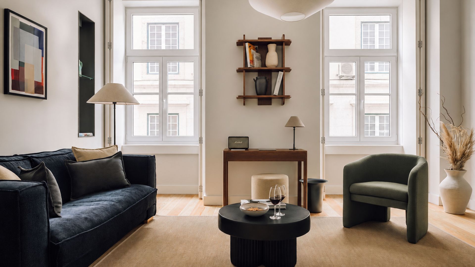 Ein modernes Wohnzimmer mit einer Couch, einem Sessel, einem Couchtisch und einem Bücherregal.