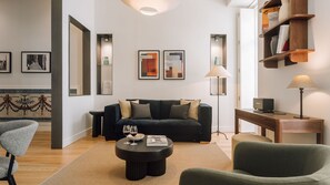 Un salon moderne avec un canapé foncé, une table basse ronde et une bibliothèque.