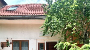 Una casa con techo de tejas, puerta principal y un patio con mesa y sillas.