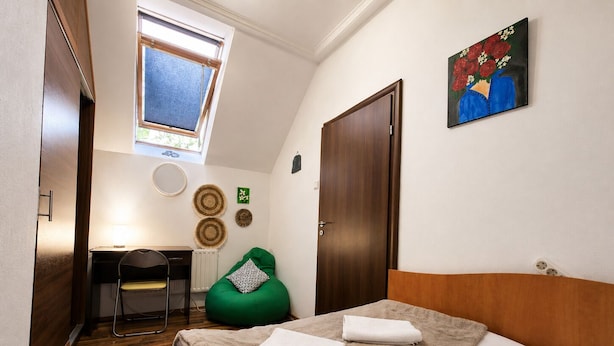 Un dormitorio con cama, escritorio, silla, ventana y puerta.