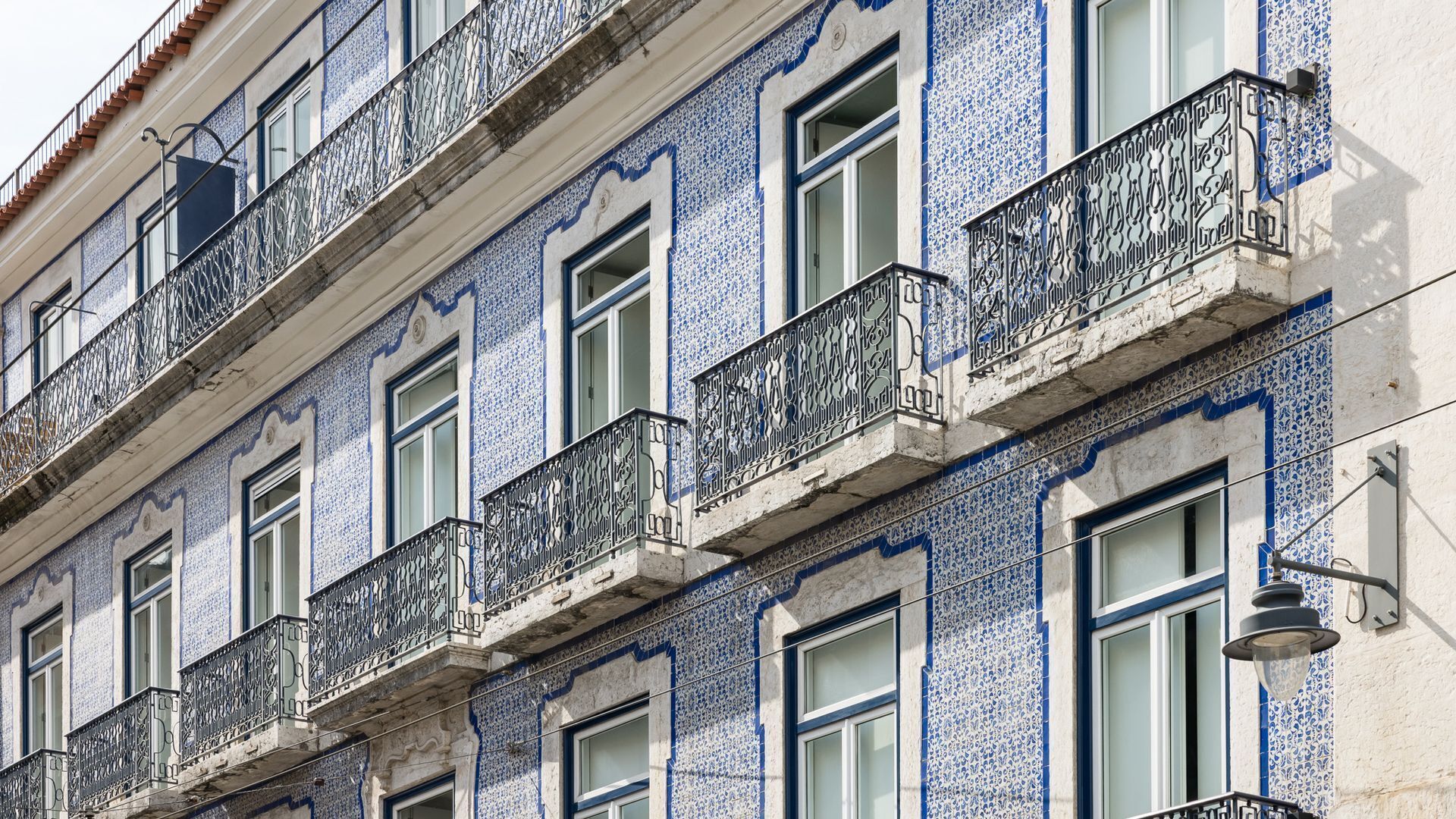 A building facade with multiple windows and balconies, featuring intricate blue and white tile patterns.