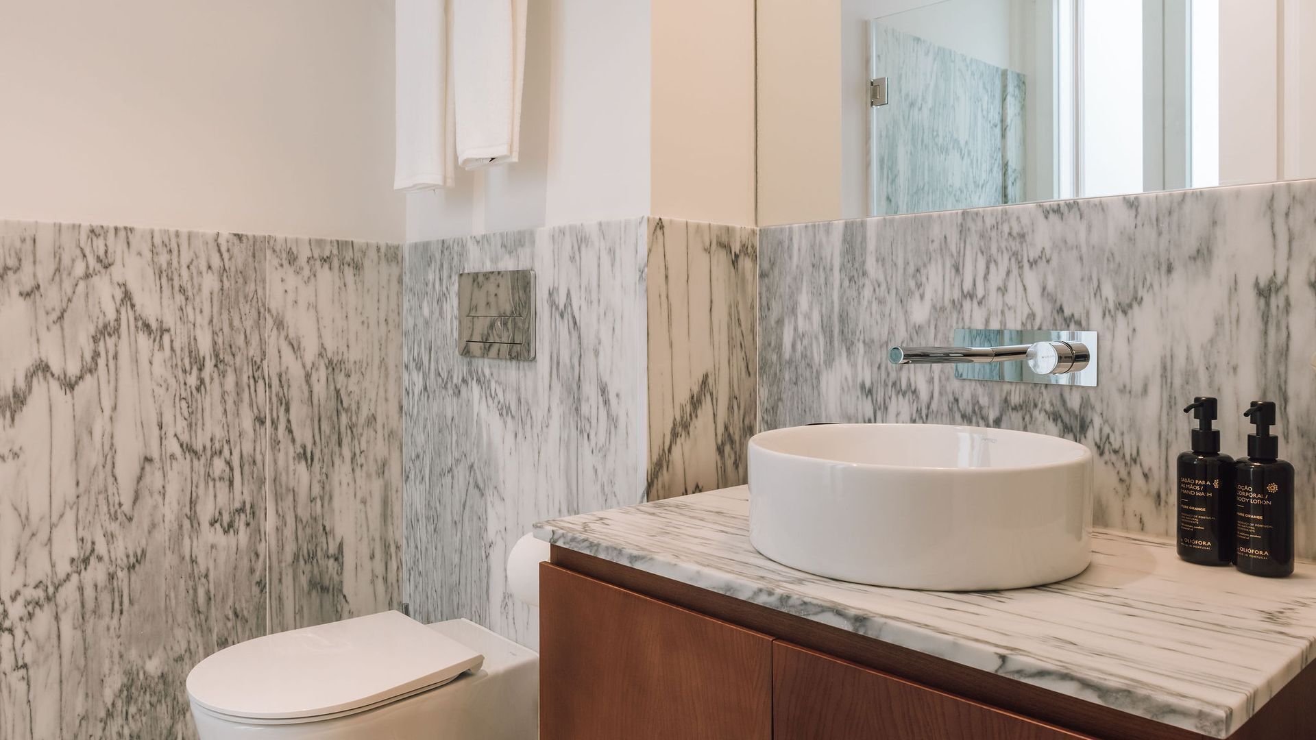 Une salle de bain avec un lavabo en marbre, des toilettes et un miroir.