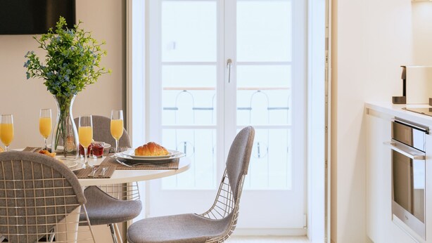 En matplats med ett bord dukat för frukost, inklusive croissanter, glas för juice och en vas med blommor.