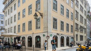 A corner building with multiple Starbucks outlets, outdoor seating, and a cobblestone street. - Ando Living - Santa Justa 79 House - 501 (Lisboa)