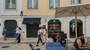 A cobblestone street with outdoor seating, a Starbucks, and an Ando Living store. - Ando Living - Santa Justa 79 House - 501 (Lisboa)