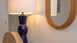 Een kamer met een houten vloer, een ronde spiegel en een lamp met een witte lampenkap.
