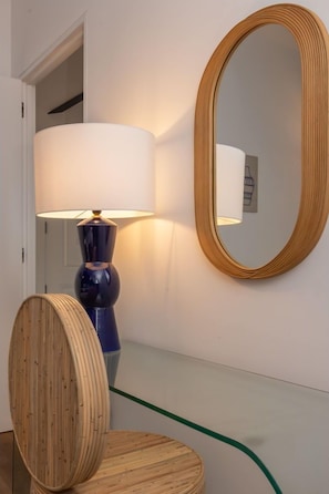 A room with a wooden floor, a round mirror, and a lamp with a white lampshade. - Santa Justa 77 Flats - 601 (Lisboa)