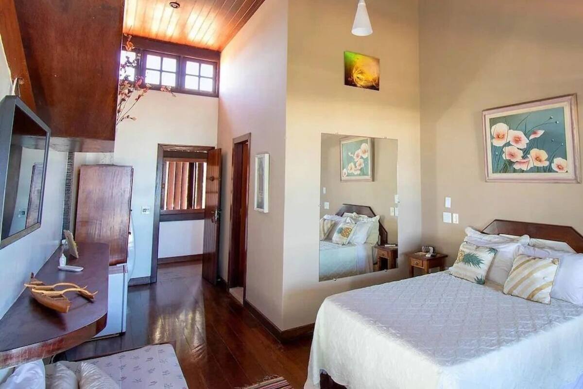 A bedroom with a large bed, a desk with a chair, and a mirror on the wall.