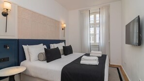 Ein Hotelzimmer mit Bett, Nachttischen, einem Fernseher und einem Fenster mit Vorhängen.