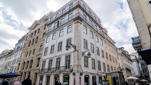 Un edificio de varios pisos con entrada en esquina, ventanas amplias y balcones.