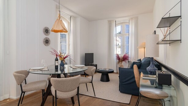 Un comedor moderno con una mesa de vidrio, sillas y una lámpara colgante.