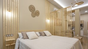 Une chambre à coucher avec un lit, des lattes en bois, une lampe fixée au mur et une petite table avec un lampadaire.