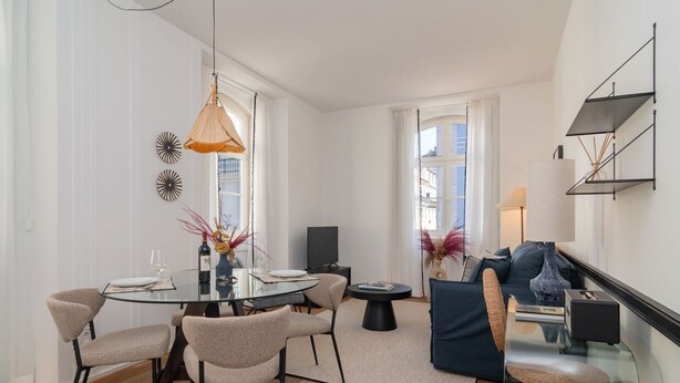 Un salon moderne avec une table ronde en verre, des fauteuils beige, un canapé bleu foncé et une table basse.