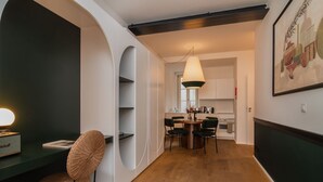 A modern kitchen with white cabinets, a dining area with a round table and chairs, and a hanging light fixture. - Ando Living - Santa Justa 77 House - 401 (Lisboa)