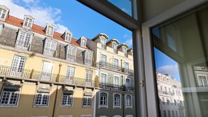Filare di edifici a più piani con balconi, cielo sereno e un telaio di finestra.
