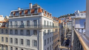 Un edifici de diversos pisos amb un balcó, grans finestres i vistes a la ciutat.