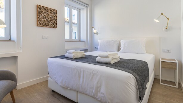 Et moderne hotelværelse med en stor seng, et natbord, en stol og et vindue med udsigt.