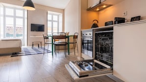 Una cocina moderna con horno empotrado, un comedor con mesa y sillas, y un gran ventanal que proporciona luz natural.