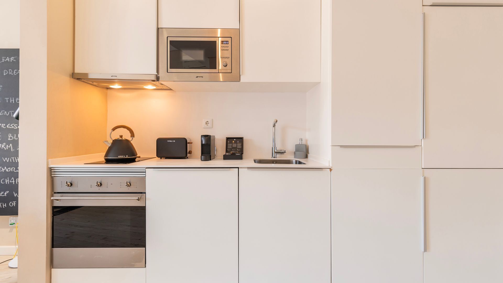 Eine moderne Küche mit Mikrowelle, Wasserkocher, Toaster und Kaffeemaschine auf der Arbeitsplatte.