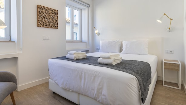 Une chambre d’hôtel moderne avec un grand lit, une table de chevet, une chaise et une fenêtre donnant sur un beau paysage.