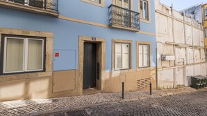 Un bâtiment à la façade bleue, une porte portant le numéro « 28 », et une fenêtre sur laquelle est affiché un panneau indiquant « S.I. ».