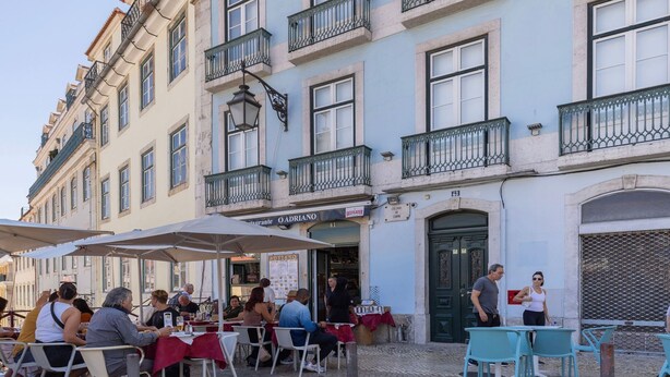 A restaurant with outdoor seating, a sign for 'OADRIANO', and a green door. - Carmo 43 | Apartamento 104 (Lisboa)
