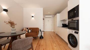Un espacio habitable compacto con kitchenette, zona de comedor y sofá.