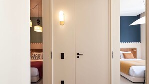 A hotel room with a double door, a bed with a headboard, and a bedside table. - Ando Living - Santa Catarina Townhouse - 102 (Porto)
