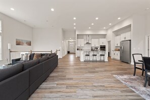 Una cocina moderna con armarios blancos, un refrigerador de acero inoxidable y una isla central con taburetes de bar.