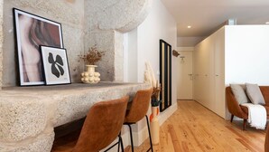 Een modern interieur met een stenen muur, kunstwerken in lijsten en een zithoek met een bank en stoelen.