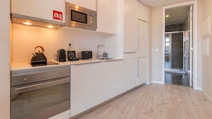 A modern kitchen with a microwave, kettle, toaster, and a small sink. - Carmo 43 | Apartamento 201 (Lisboa)