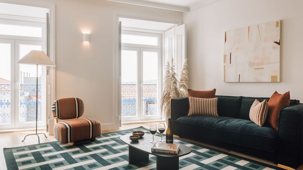 Ein Wohnzimmer mit Sofa, Couchtisch, Lampe, Fenster mit Aussicht und einem Bild an der Wand.