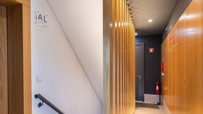 A hallway with a wooden door, a fire extinguisher, and a sign on the wall. - Garcia 28 | Apartment 4A by LovelyStay (Lisboa)